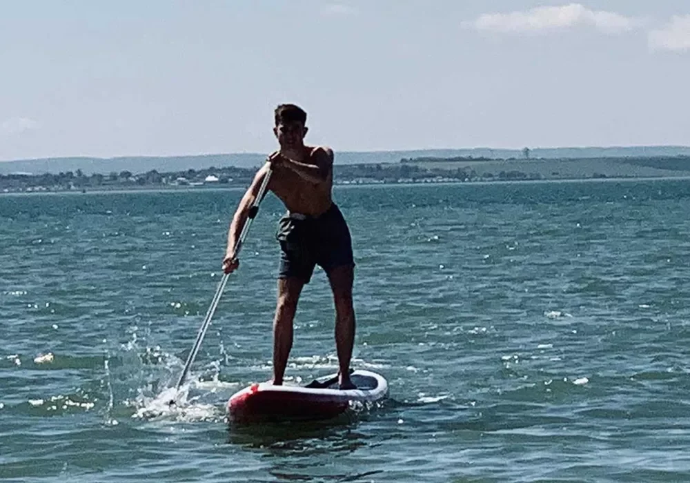 Sörf tahtası üzerinde kürek tutan bir adam