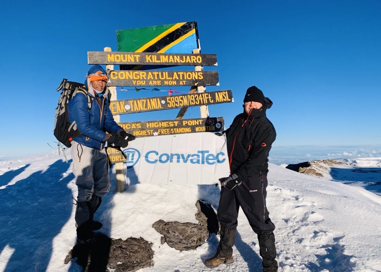 two people posing outside in the snow with a convatec sign 