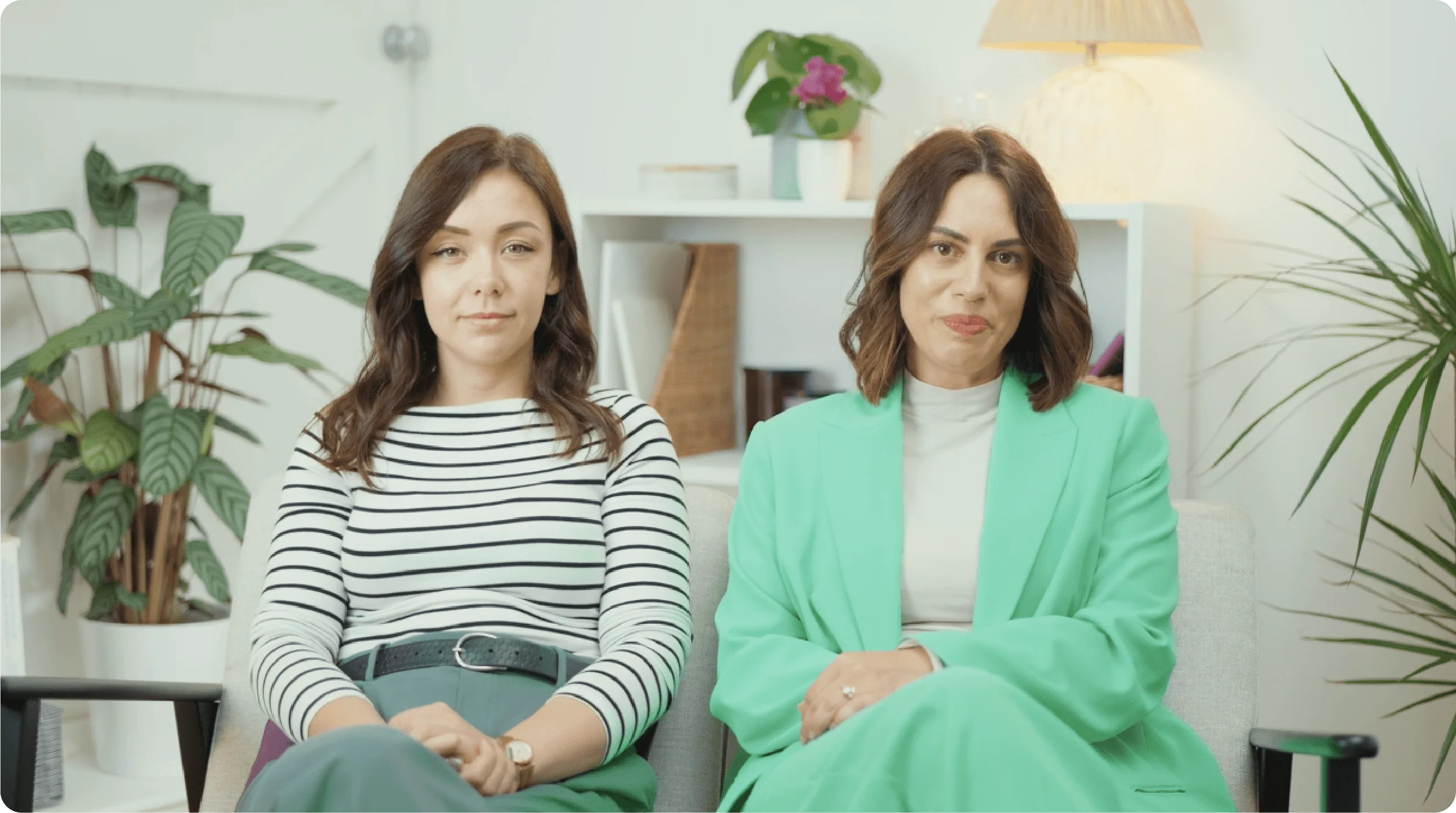 a couple of women sitting next to each other and looking at the camera